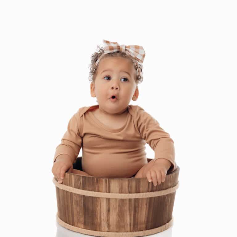 Petite fille de 9 mois dans un baquet en bois, séance photo grand bébé