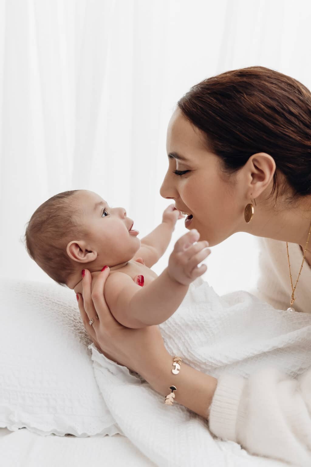 Maman qui fait sourire son bébé de 2 mois, séance photo bébé éveil au studio Amélie Soubrié près de Paris