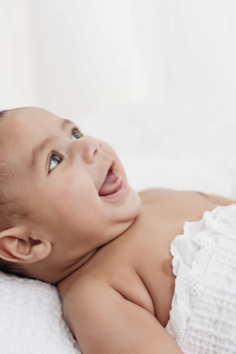 Bébé de 3 mois qui rit aux éclats, allongé sur le ventre