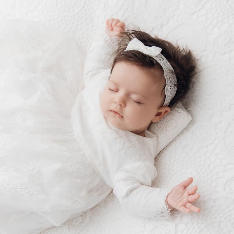 Bébé avec un bandeau, endormi paisiblement sur un drap blanc