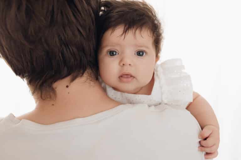 Bébé de 2 mois qui regarde par-dessus l'épaule de sa maman