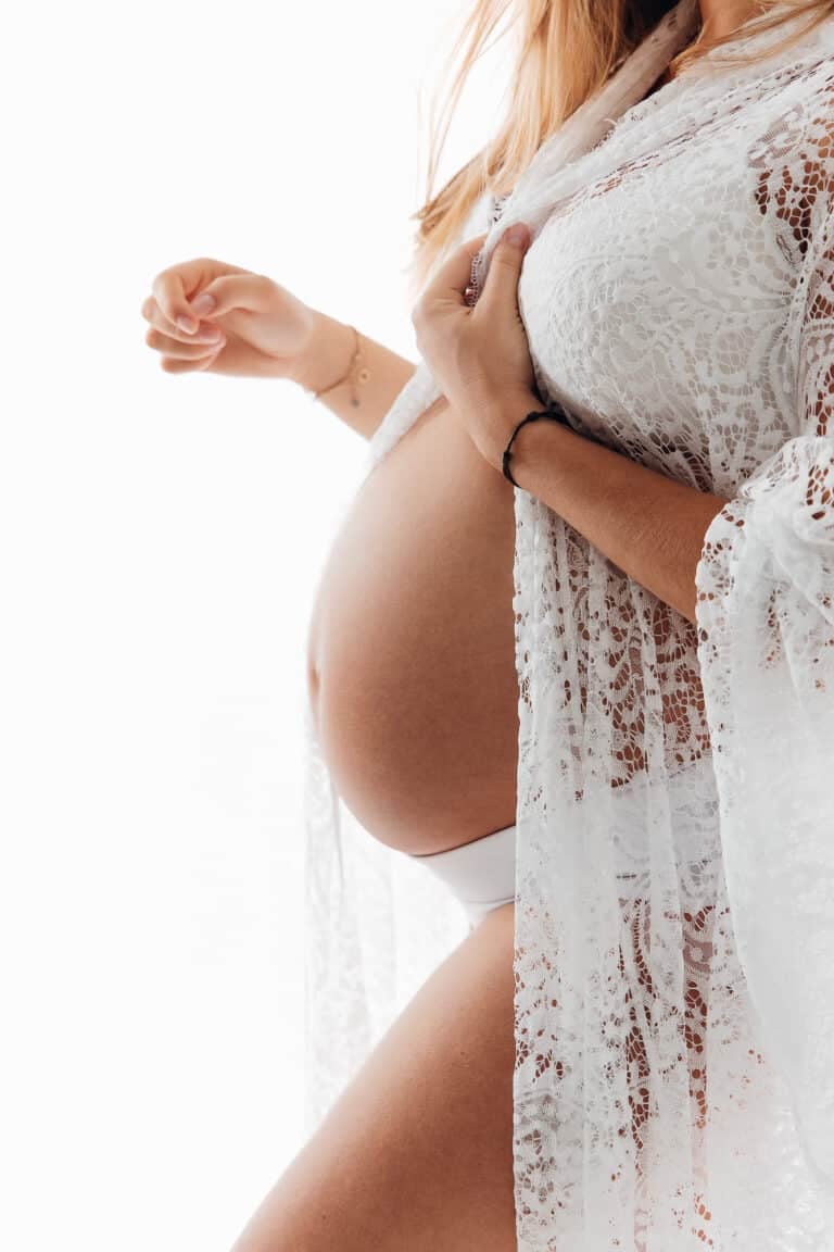 Future maman en voile de dentelle blanche, séance photo grossesse au studio Amélie Soubrié près de Paris