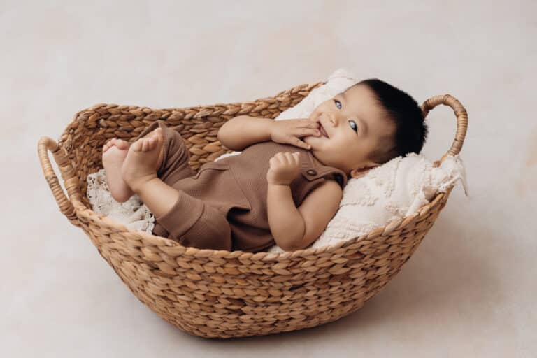Bébé installé dans un panier en osier, pose sécurisée en contenant pendant une séance photo bébé 2 mois