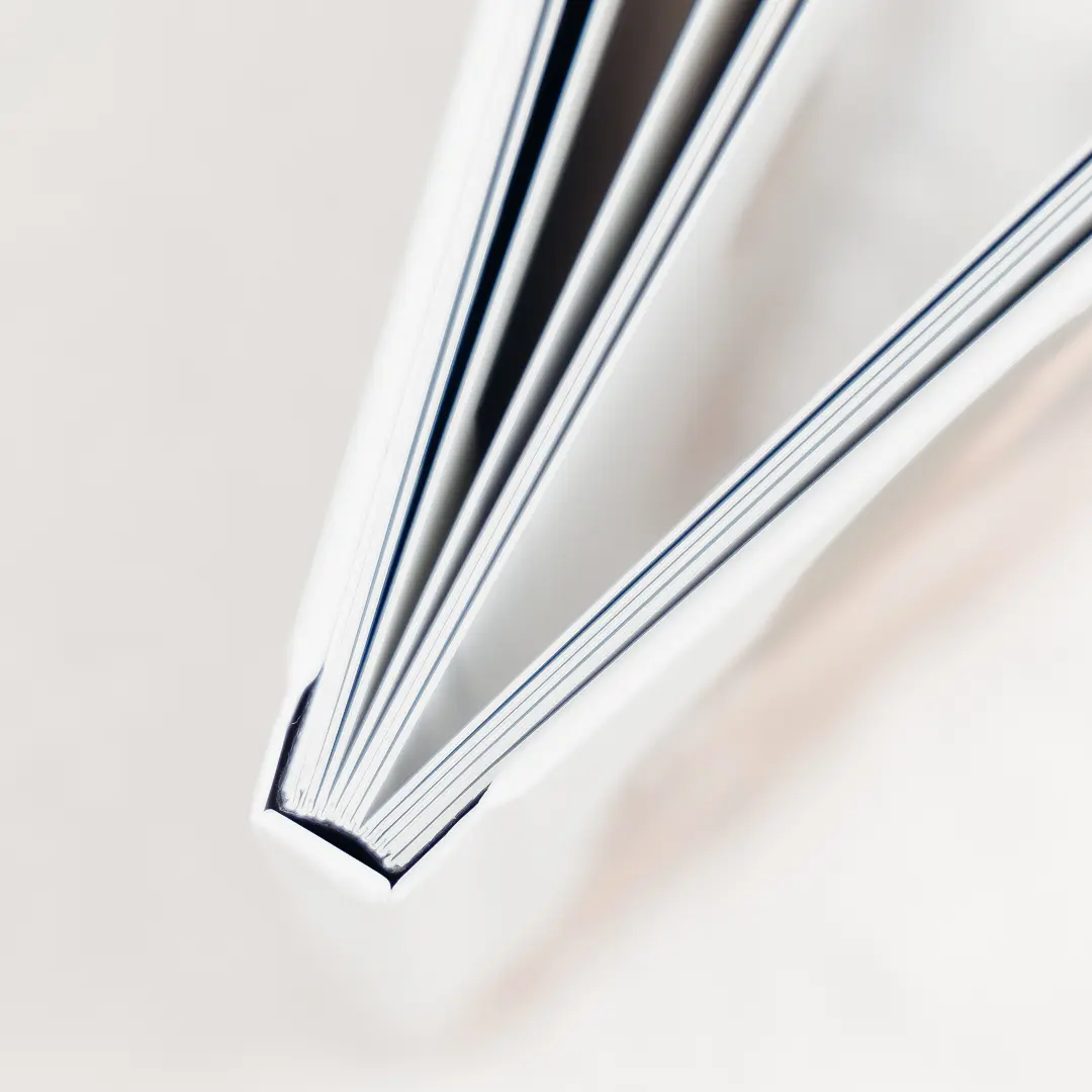 Livre photo posé légèrement ouvert, pages blanches nettes sur fond clair. Alt text mettant en valeur le thème photo et le soin du détail.
