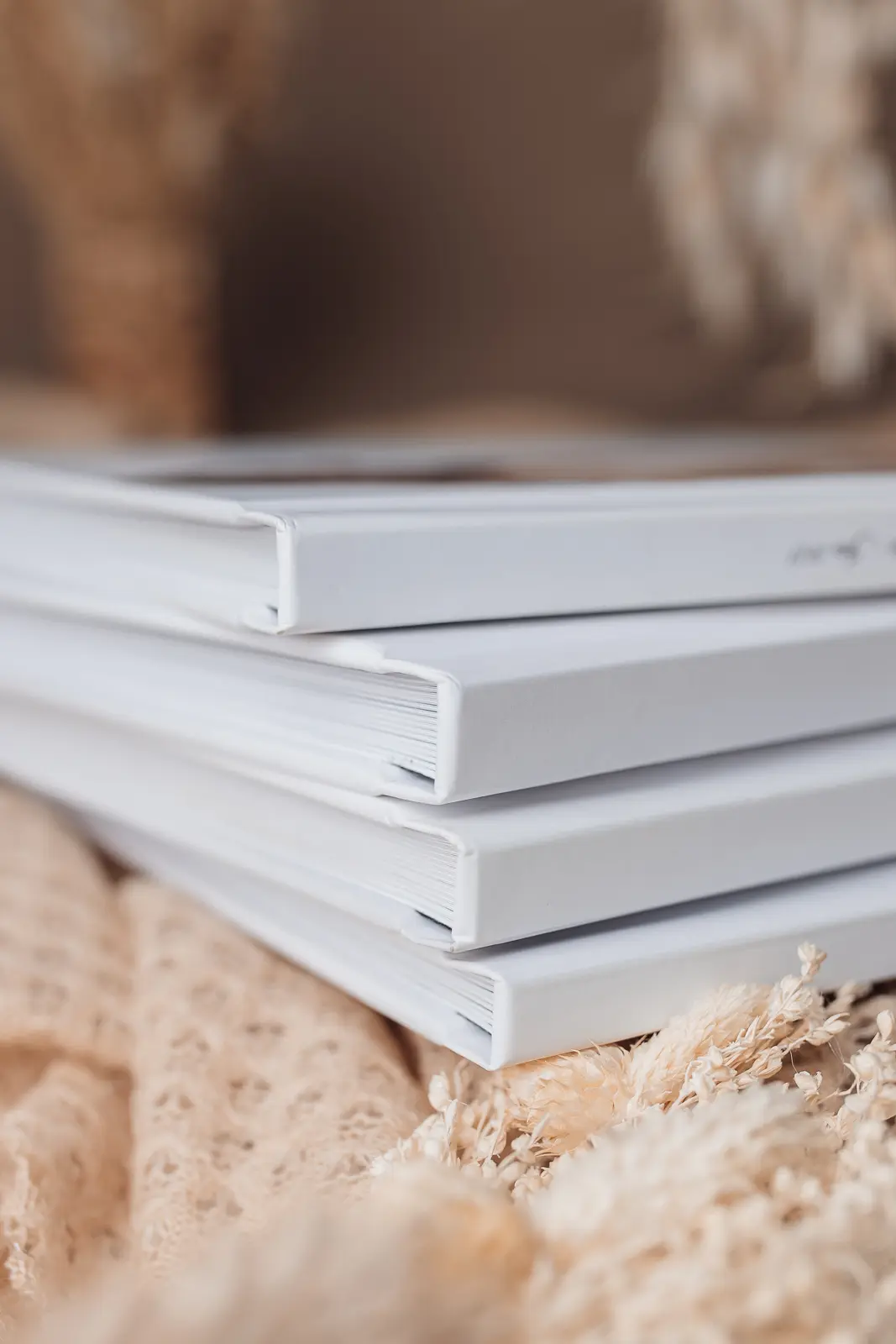 Livres photo empilés sur un support; textures naturelles et décor miel en arrière-plan.
