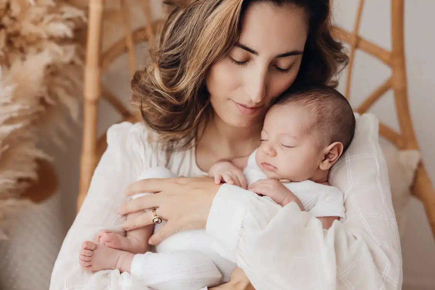 Mère tenant son bébé endormi dans les bras, entourés d’une aura douce et chaleureuse, dans un cadre intérieur.