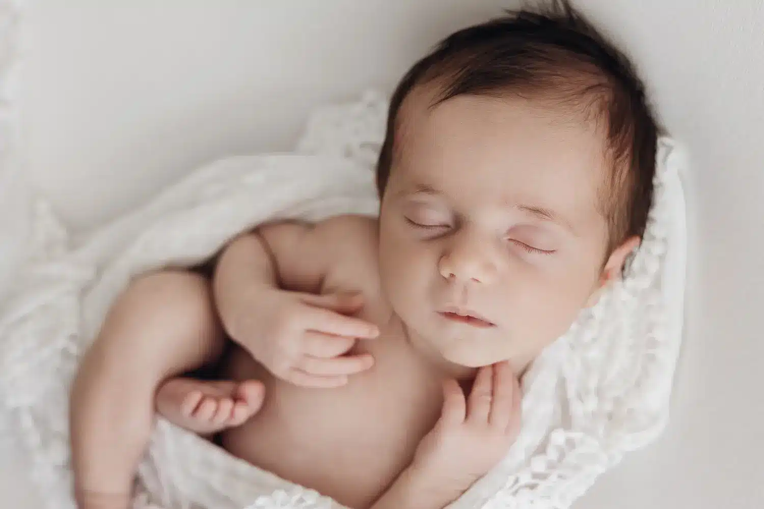 Baby endormi dans une composition douce, enveloppé dans une couverture blanche.