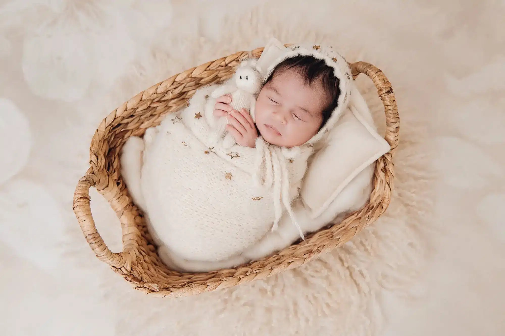 Nouveau-né endormi dans un panier en osier, enveloppé dans une couverture blanche et un bonnet, ambiance douce et cosy.