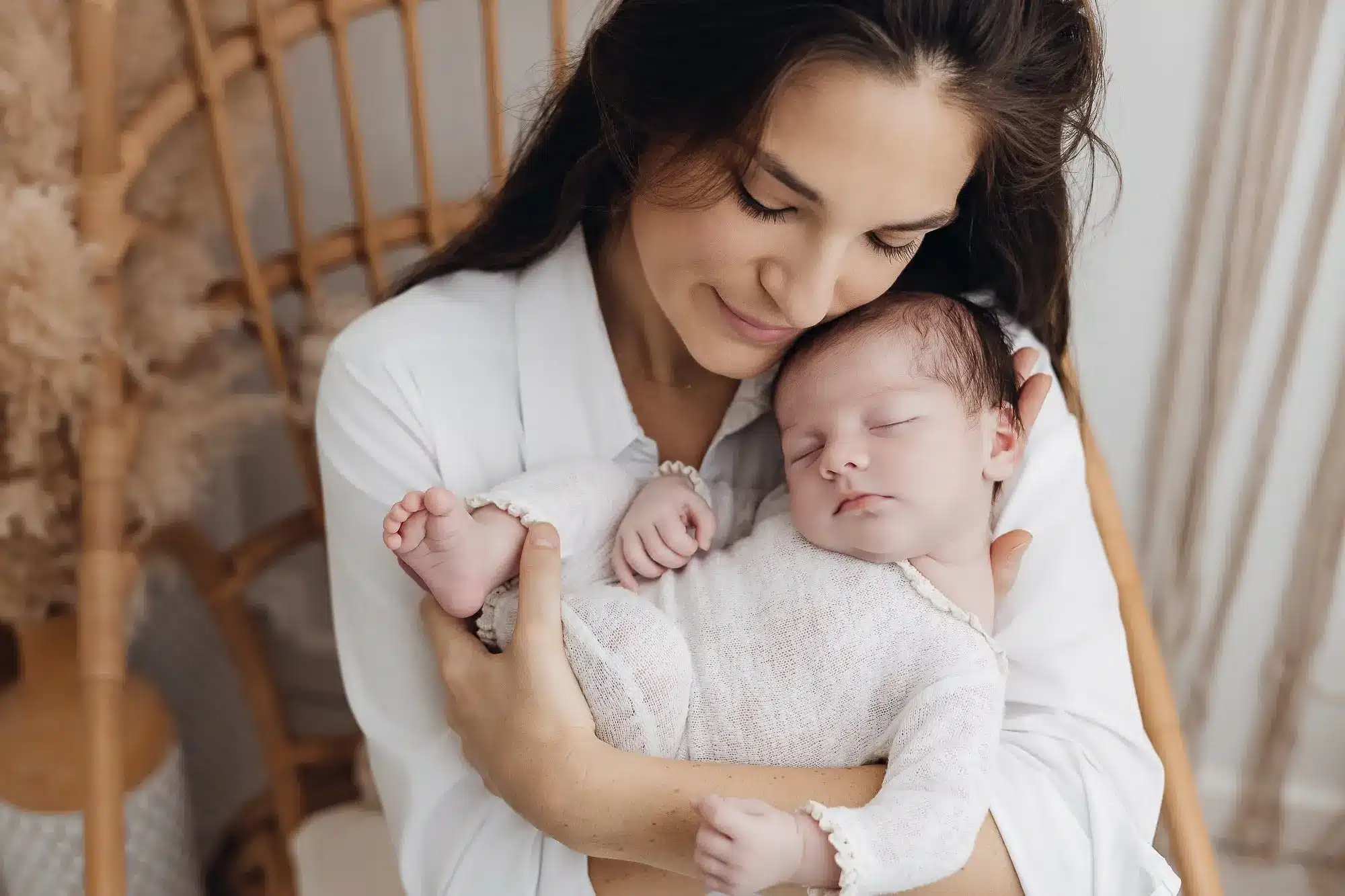 Portrait tendre d’une mère tenant son bébé endormi, douceur et confort au studio. alt texte pour photographie de grossesse et nouveau-né.