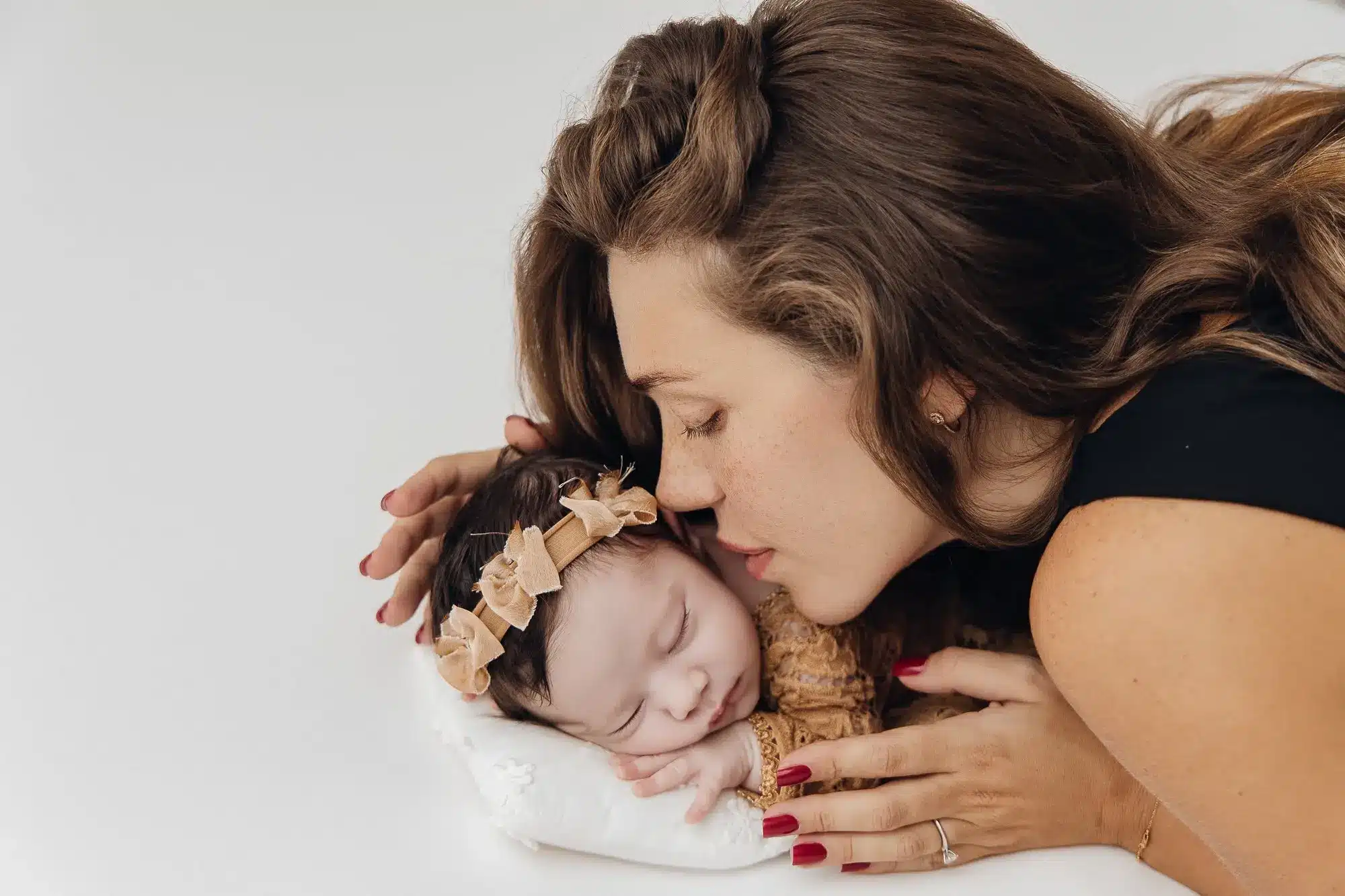 Mère souffle doucement près un bébé endormi sur un petit oreiller, tête inclinée, mère et enfant en geste tendre.