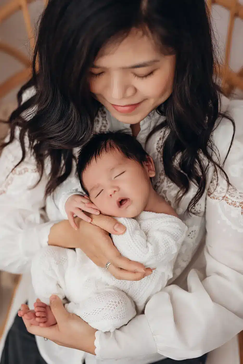 Maman souriante qui tient son nouveau-né contre elle, séance photo naissance au studio